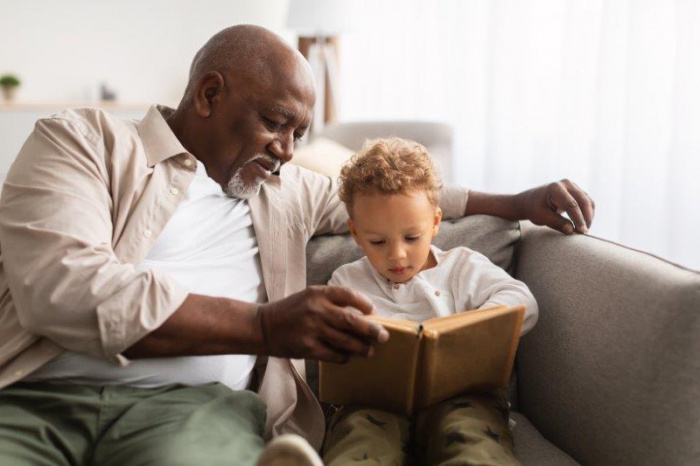 A grandfather reading a book with his grandson