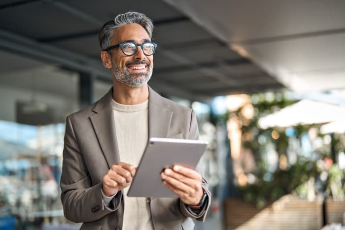 Happy middle aged professional business man executive manager using tablet.
