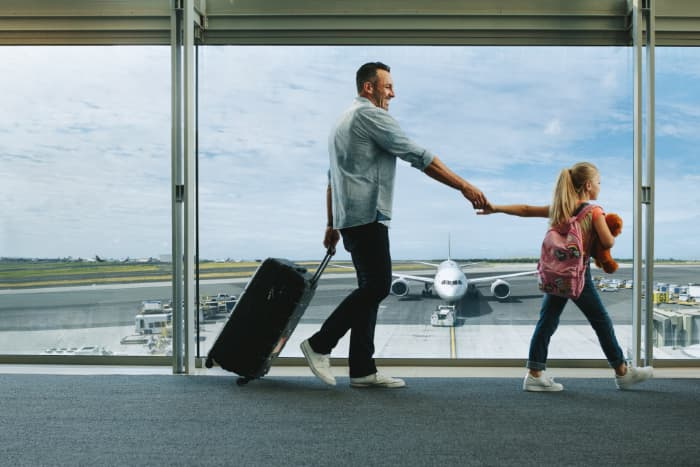 Girl holding hand of her father and walking to board their flight at airport. Father and daughter going on a vacation.