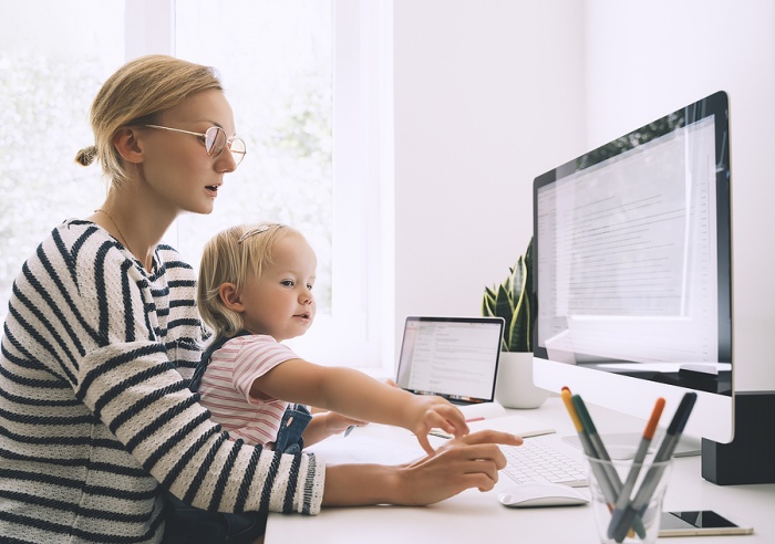 a young work-from-home stay-at-home mom at her computer with her young daughter