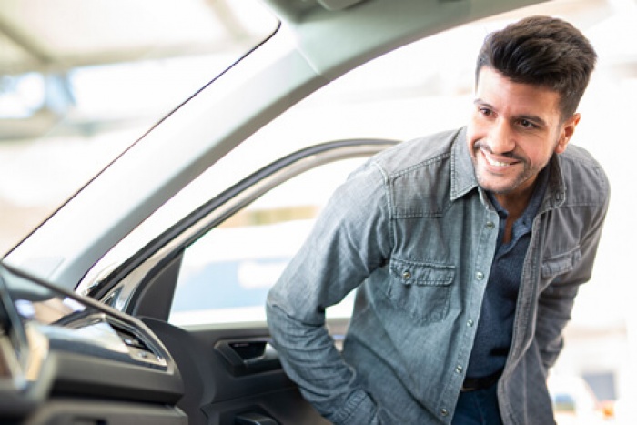 man smiling looking inside a new car he wants to purchase with a 72-month auto loan