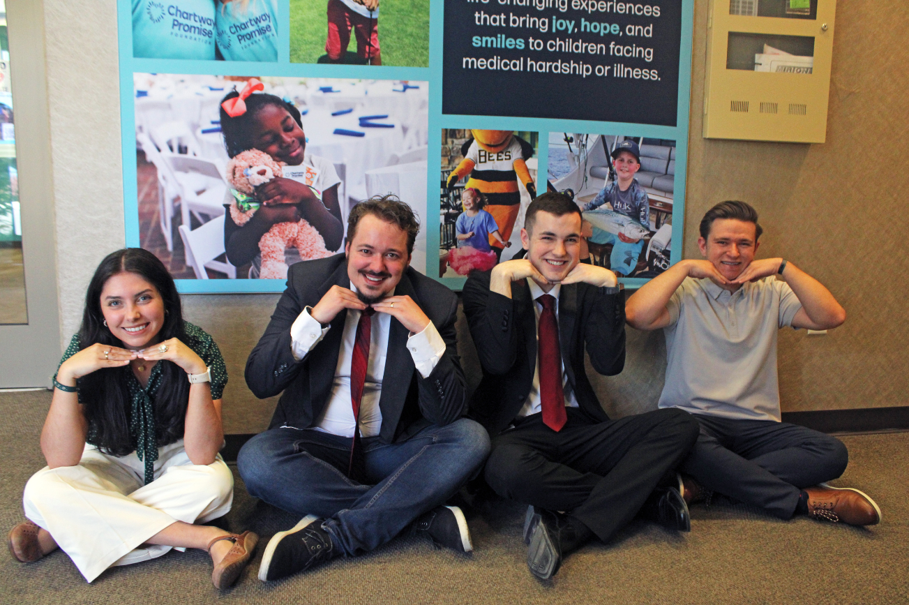 Chartway interns sitting on the ground and smiling at the South Jordan office